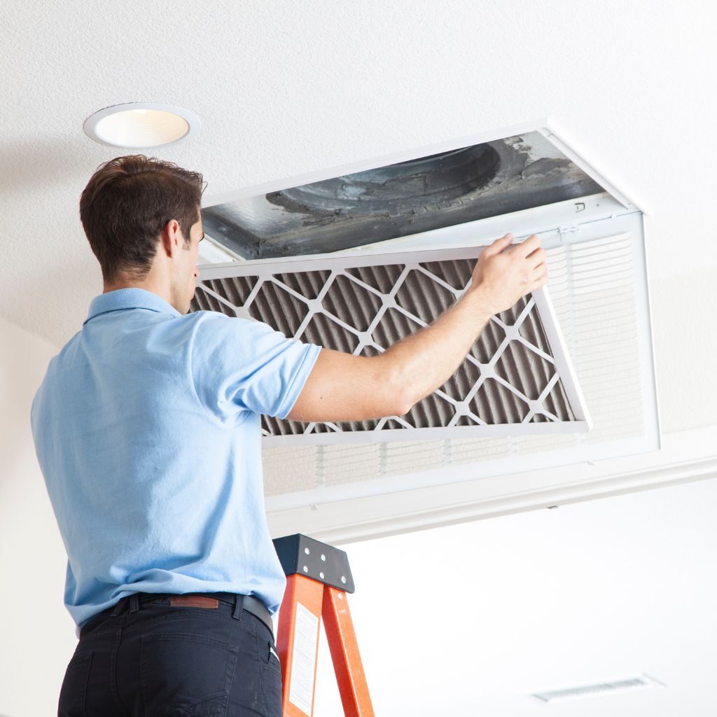 A Man Changing Air Filters on Ceiling Air Condition Unit